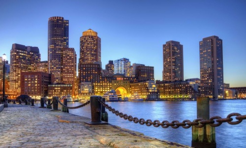 brick paved sidewalk along the water with city skyline