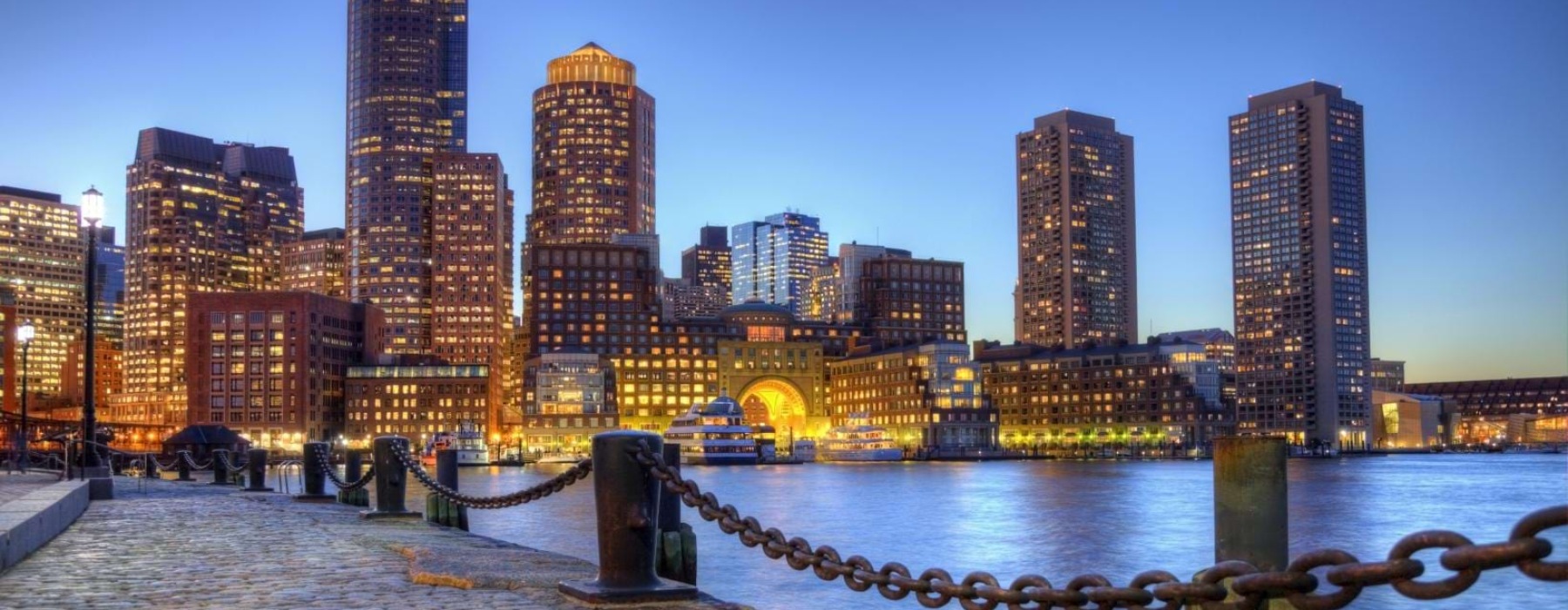 brick paved sidewalk along the water with city skyline