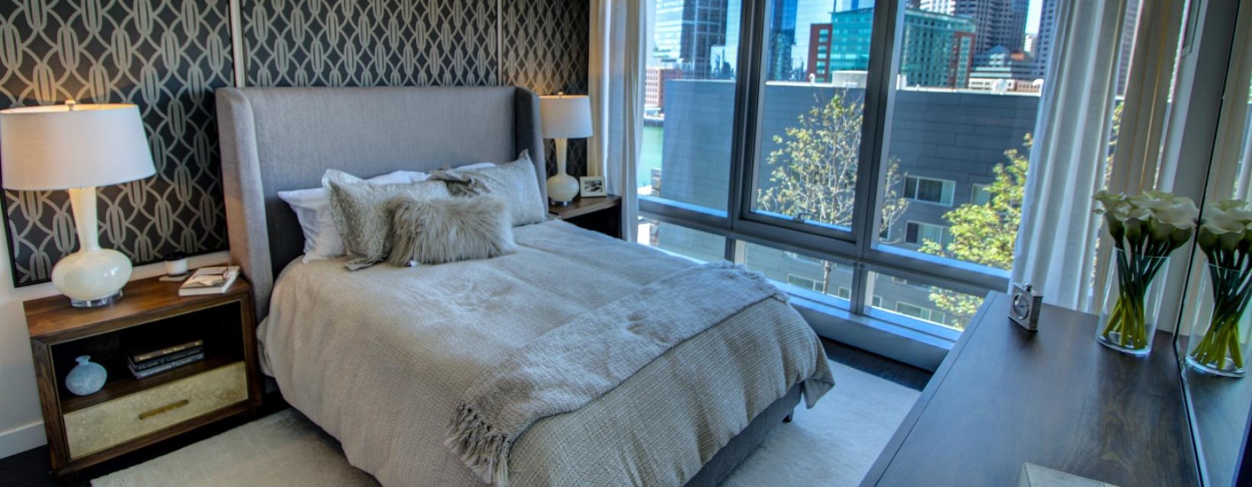 a bedroom with large windows and city views